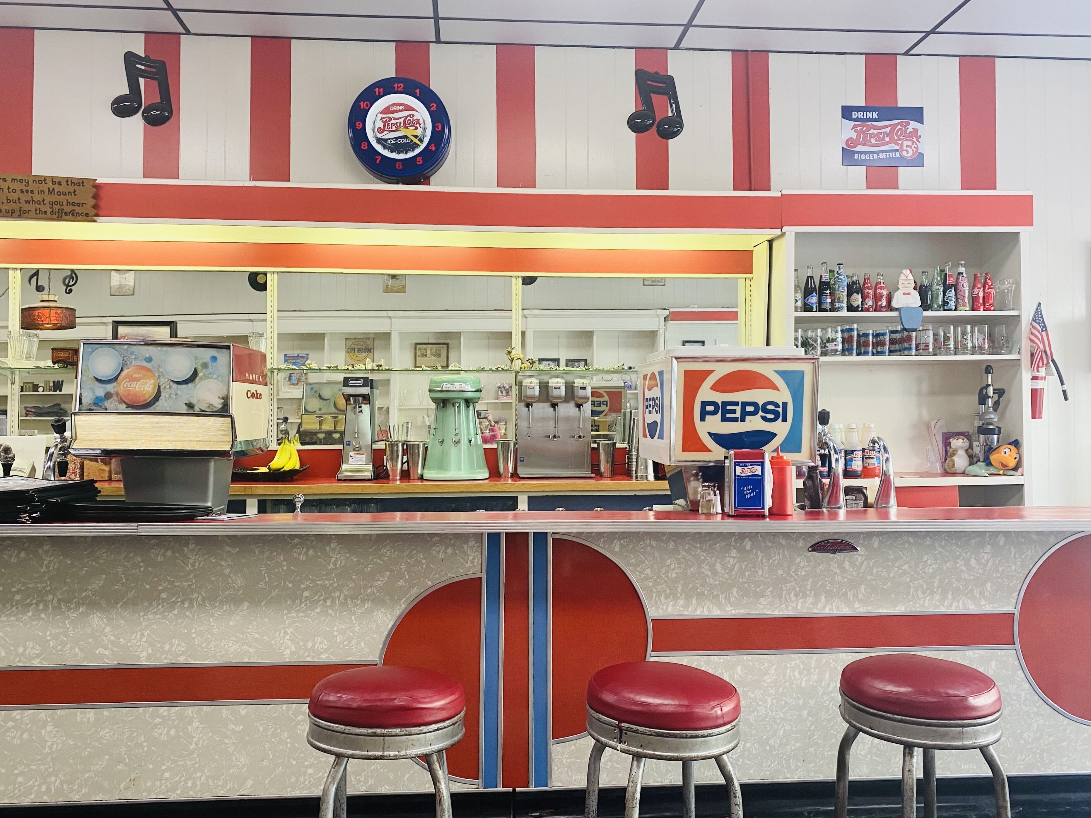 A retro-themed bar with Pepsi branding, soda dispensers, and a jukebox.