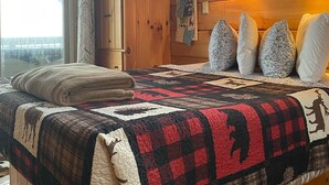 Una camera da letto accogliente in legno con un letto grande, una finestra e un armadietto di legno.