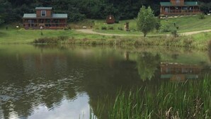 Un lodge sul lago con un edificio grande e una struttura più piccola, immerso nel verde e affacciato su un lago tranquillo.