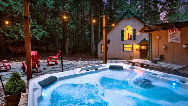 Un jacuzzi en un área boscosa con un edificio de madera y un cartel que dice 'SPA RULES'.
