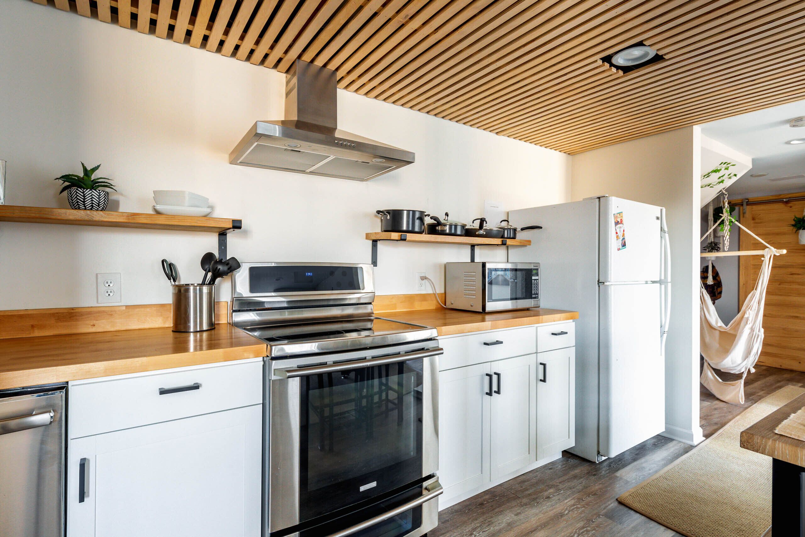 Una cocina moderna con electrodomésticos de acero inoxidable, encimeras de madera y armarios blancos.