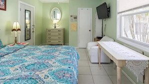 Ein Schlafzimmer mit Bett, Kommode, Nachttisch und Fernseher an der Wand.