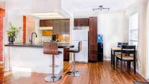 Une cuisine moderne dotée d’un îlot central, de tabourets de bar et d’un coin repas avec des chaises.