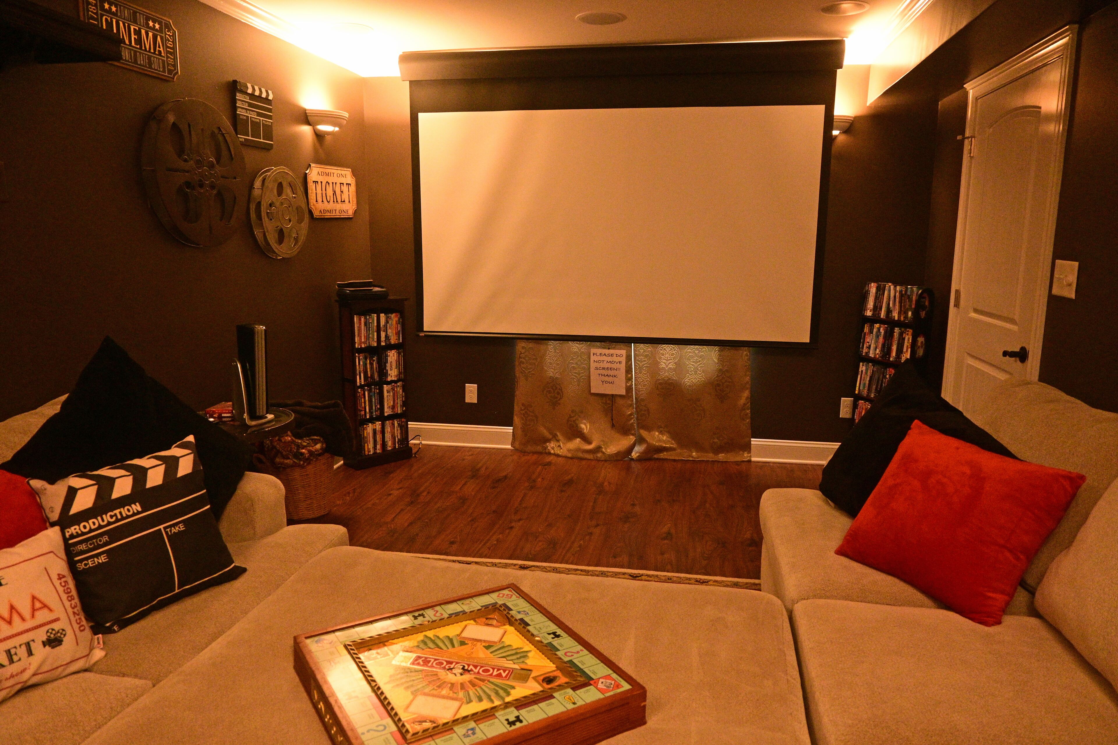A home theater room with a large screen, a projector, and a popcorn bucket.