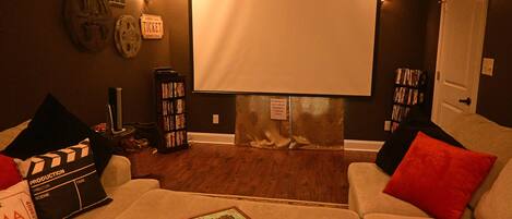 A home theater room with a large screen, a projector, and a popcorn bucket.
