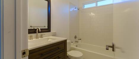 A bathroom with a white sink, vanity, and toilet.