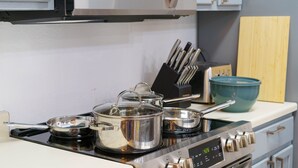 A kitchen with a stove, pots, a microwave, and a set of knives. - Family Friendly & King Suite & Fire Pit, 9 Mil DT (Austin)