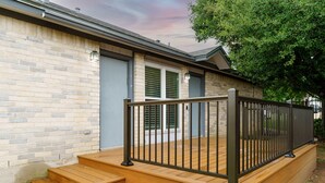A brick house with a wooden deck and a black metal railing. - Family Friendly & King Suite & Fire Pit, 9 Mil DT (Austin)
