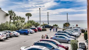 A parking lot with cars, palm trees, and a view of the ocean. - Live Like a Local Too (Miramar Beach)