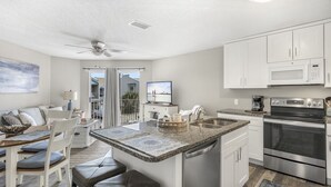 A modern kitchen with white cabinets, a stainless steel oven, and a granite countertop. - Live Like a Local Too (Miramar Beach)