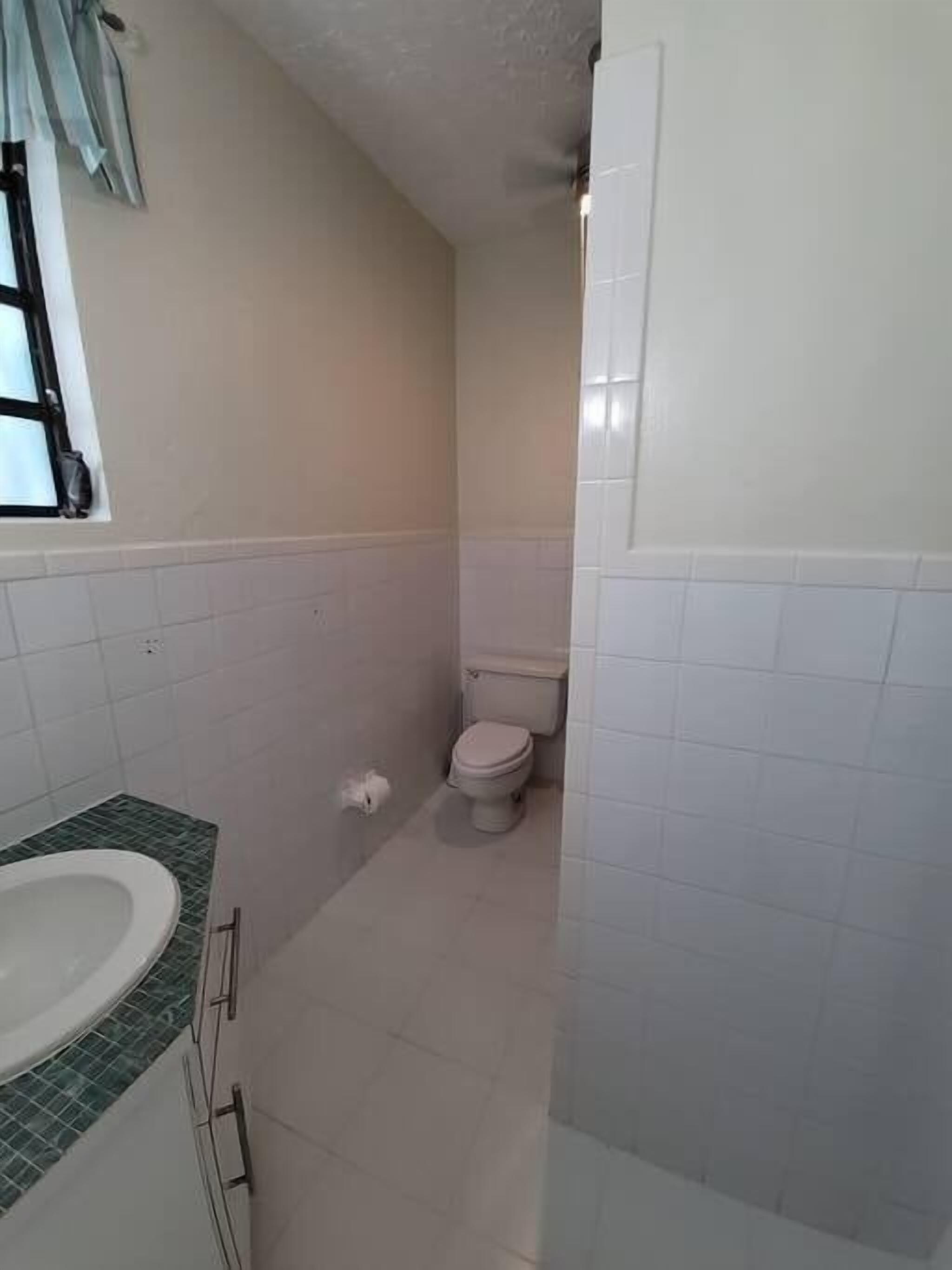 A bathroom with a toilet, sink, and tiled walls.