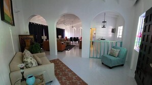 Un grand salon comprenant un canapé, un tapis à motifs et un coin repas avec des chaises et une table.