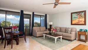 A spacious living area with a sofa, coffee table, and dining set. - Blue Horizon, One - Walk to beach & Restaurants. (East End)