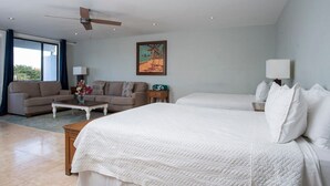 A hotel room with two beds, a sofa, a coffee table, and a painting on the wall. - Blue Horizon, One - Walk to beach & Restaurants. (East End)
