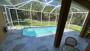 Un espacio al aire libre cubierto con piscina, suelo de piedra y una mesa de vidrio.