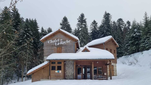 «Chalet de La Roche» -niminen puinen vuoristomaja, jossa on kiviverhous, puinen ulkoseinä ja lumipeitteinen katto.