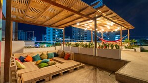 A rooftop lounge with a wooden pergola, colorful cushions, and a hammock. - Casa Chunuu hotel boutique (Santa Marta)