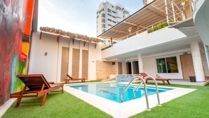 A pool area with a clear view of the pool, a wooden deck, and a building with a balcony. - Casa Chunuu hotel boutique (Santa Marta)