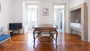 Un coin repas avec une table en bois, des chaises et un téléviseur posé sur un meuble.