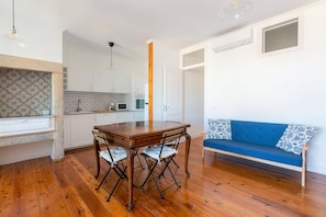 Una cocina moderna con armarios blancos, una mesa de comedor de madera y un sofá azul.