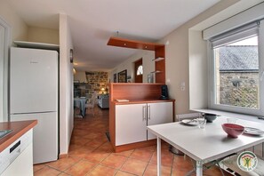Cocina compacta con refrigerador Bosch, armarios de madera y comedor con mesa y sillas.