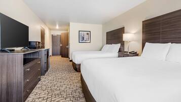 A hotel room with two beds, a TV, a desk, and a carpeted floor.