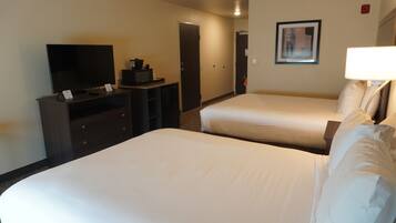 Quarto de hotel com duas camas, televisão, escrivaninha com cafeteira e quadro na parede.