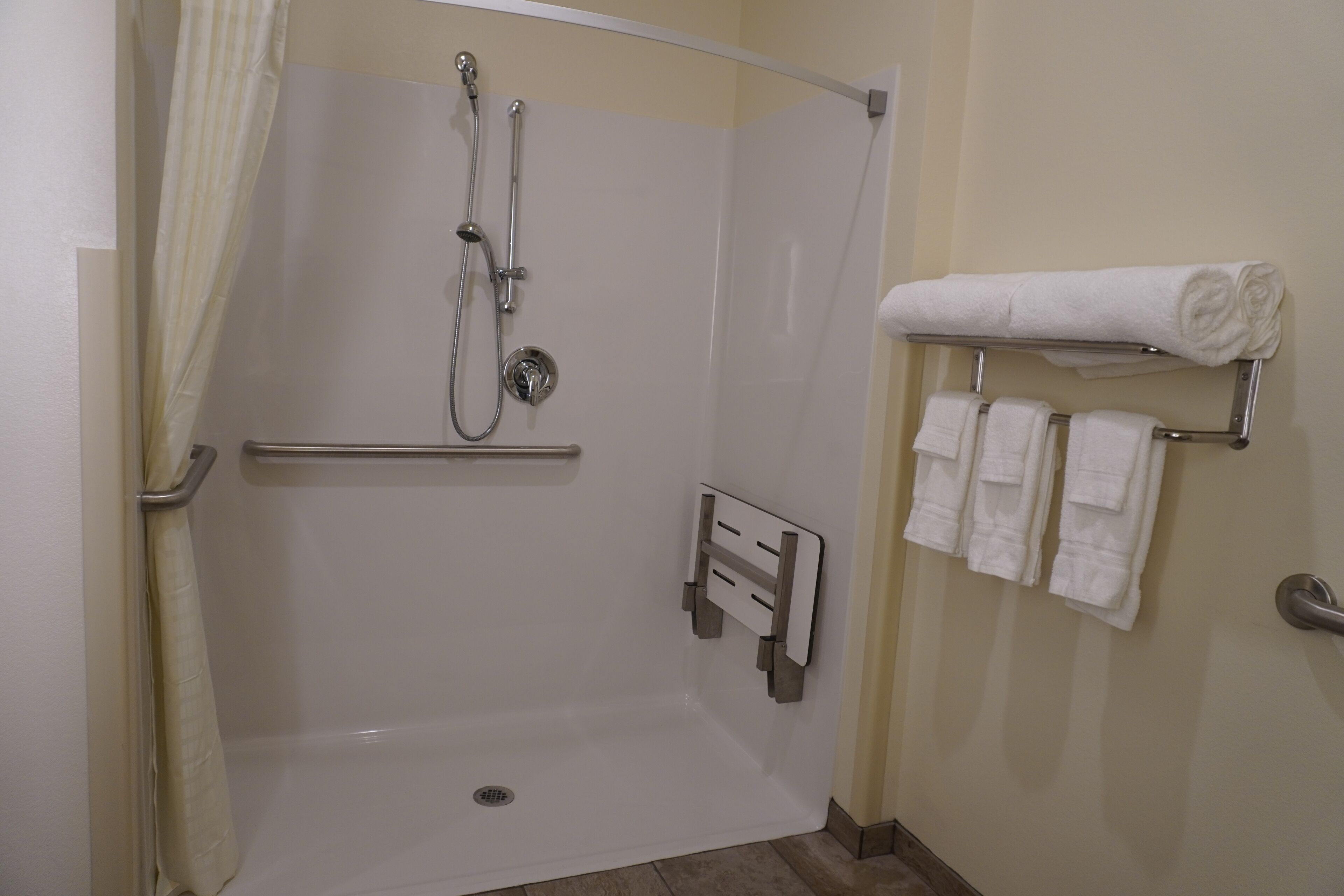 Un espace douche doté d’une porte en verre, d’un porte-serviettes avec plusieurs serviettes et d’un pommeau de douche.