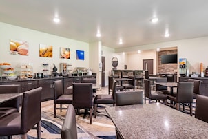 Uma área de refeições de hotel com várias mesas e cadeiras, um buffet e uma cozinha.