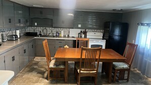 Una cocina compacta con una mesa de comedor, sillas, un refrigerador y una estufa.