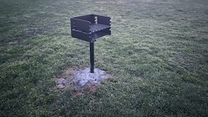 Una parrilla de barbacoa en un área exterior con césped.