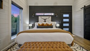 Un dormitorio con una cama grande, una ventana con vistas, una puerta y un cuadro en la pared.