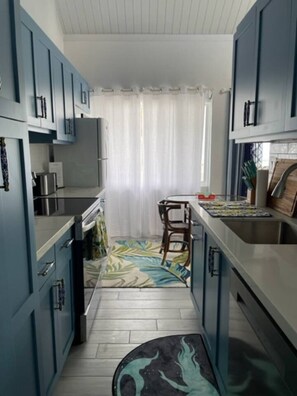 A kitchen with blue cabinets, a stove, a sink, and a chair.