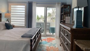 Quarto com cama, cômoda, cadeira e vista pela porta de correr.