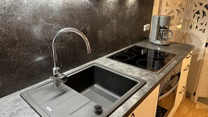 A kitchen with a double sink, a coffee maker, and a built-in stovetop.