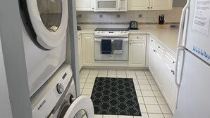 Cocina compacta con lavadora, microondas, estufa y refrigerador.