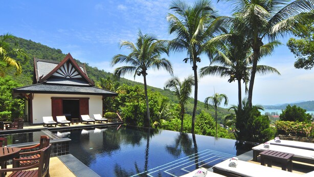A infinity pool with lounge chairs, a small building with a sloped roof, and palm trees. - Nakawanna Villa (Kamala)