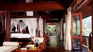 A wooden cabin with a balcony, a bed with a canopy, and a dining area with a table set for two. - Nakawanna Villa (Kamala)