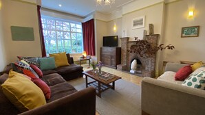 A living room with a fireplace, sofas, a coffee table, and a television. - Large beautiful unusual house with lots of character and art on the walls. (Bournemouth)