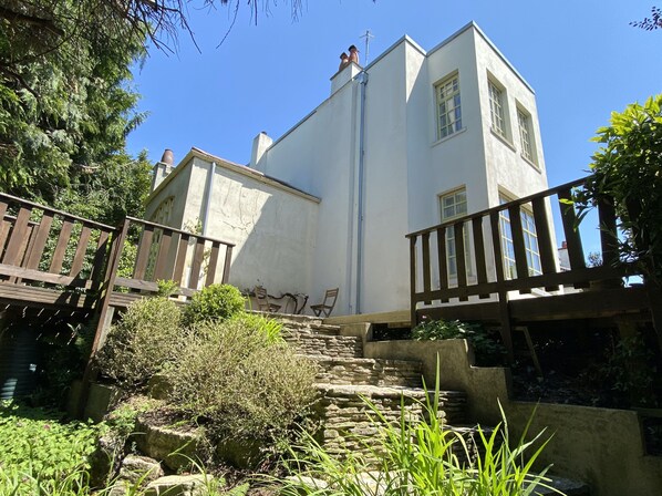 Un bâtiment à deux étages avec un escalier en pierre menant à une terrasse en bois.
