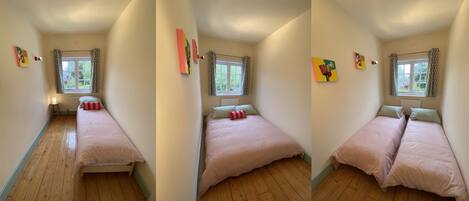 Quarto com duas camas, janela com cortinas, radiador e decoração nas paredes.