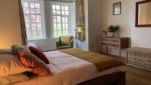 A bedroom with a large bed, a chair, a dresser, and a radiator. - Large beautiful unusual house with lots of character and art on the walls. (Bournemouth)