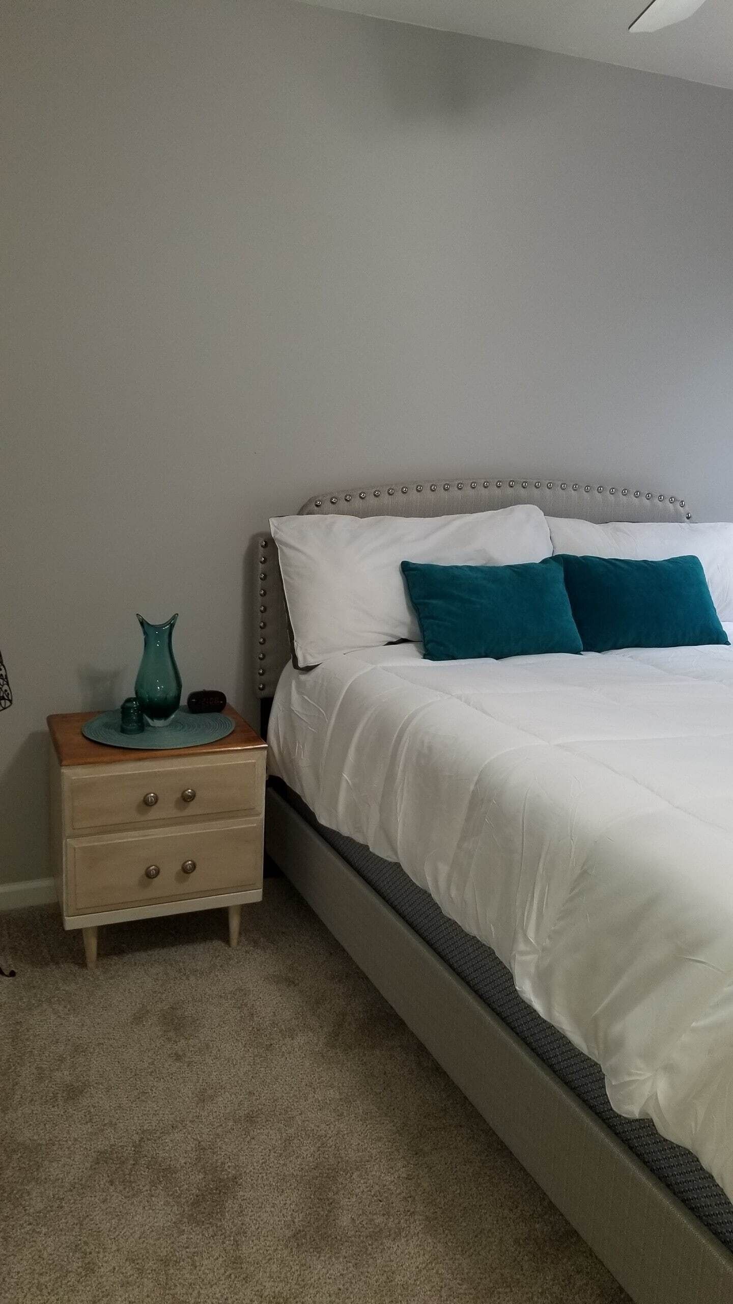 Un dormitorio con una cama, una mesita de noche y un aparador.