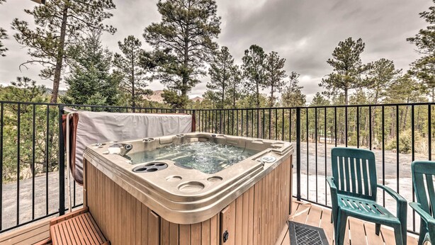 Een hottub op een houten terras met uitzicht op bomen en bergen.