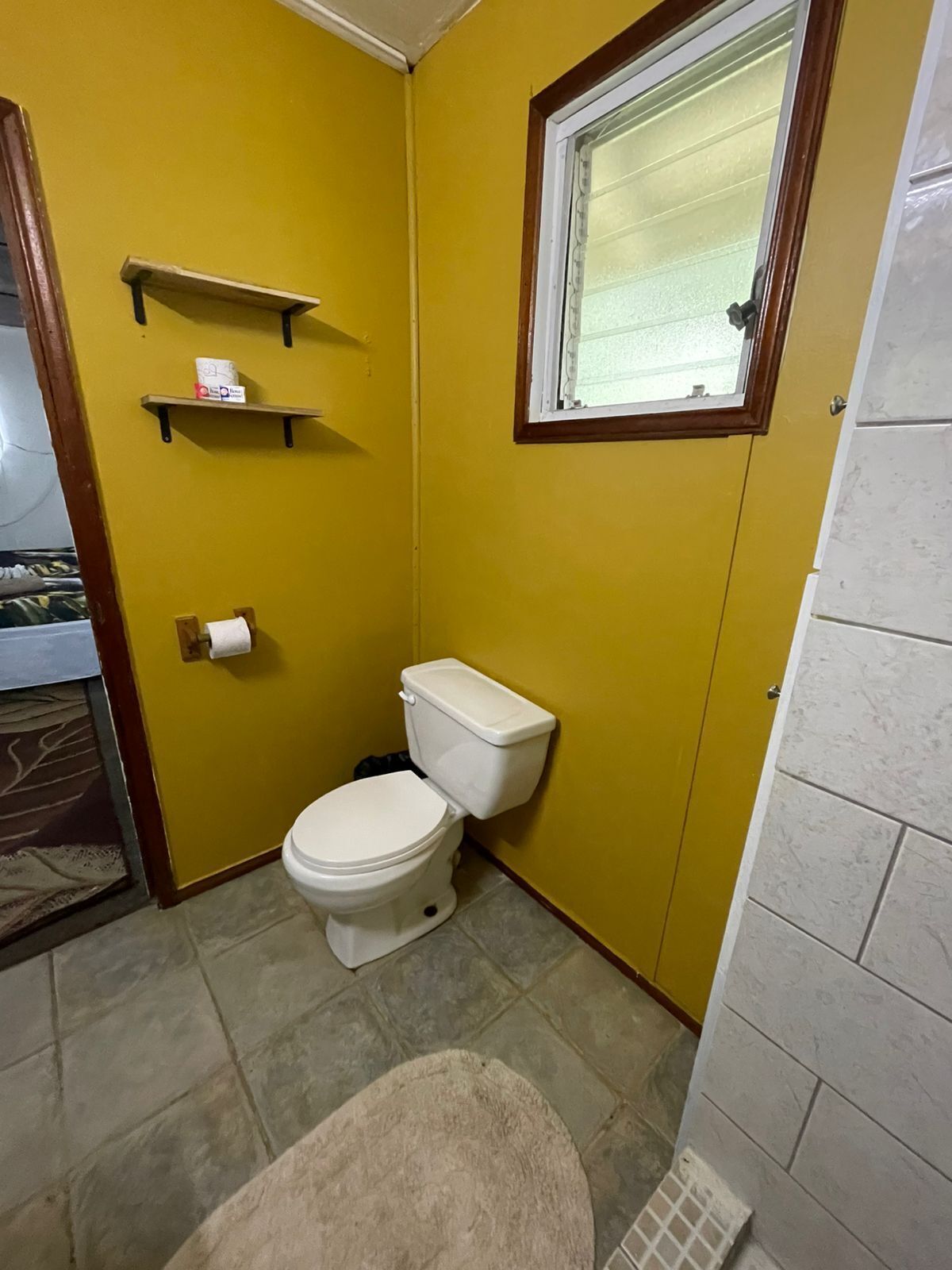 Un baño pequeño con inodoro, ventana y perchero.