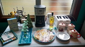 Una encimera de cocina con varios objetos, incluyendo una cafetera, un tostador y un pequeño árbol de Navidad.