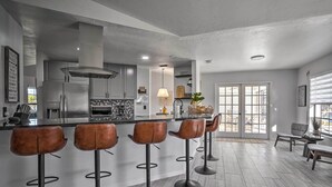 Una cocina moderna con una isla central, taburetes de bar y un comedor con vistas.