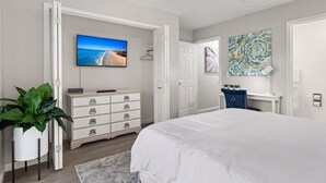 A bedroom with a bed, a dresser, a TV, and a plant. - Spacious 2 bedroom condo (North Charleston)