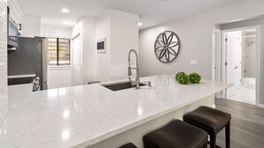 A modern kitchen with a large island, stainless steel appliances, and a decorative wall piece. - Spacious 2 bedroom condo (North Charleston)