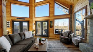 A spacious living room with a large brown leather sofa, a coffee table with a plant and two cups, and a stone fireplace. - BeautifulMtViewResortIndoorPool/Spa2CabinsPFNearIsland/Strip Game Room 16-18ppl (Pigeon Forge)